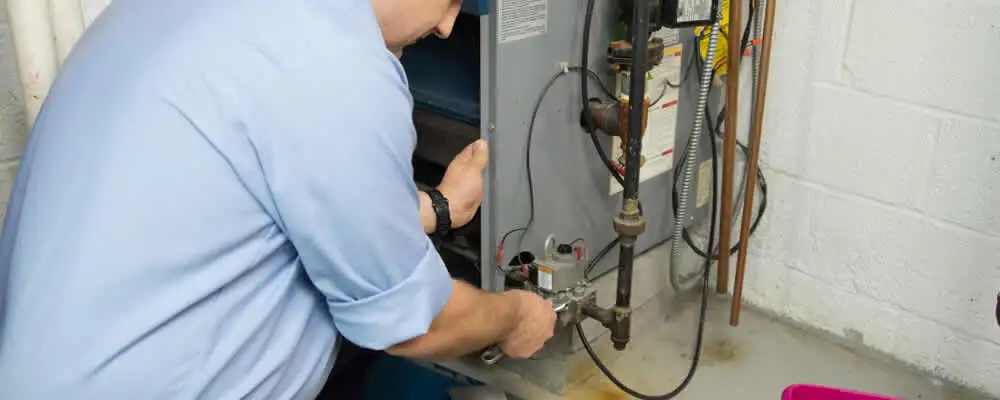 Furnace repair technician inspecting and servicing a home heating system in Bloomington, IN