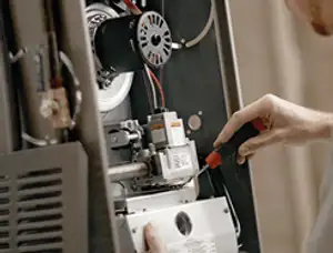 Furnace repair technician inspecting internal components and wiring in Bloomington, IN