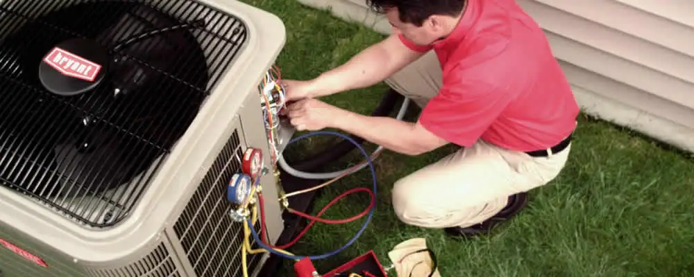 HVAC technician servicing an outdoor air conditioner unit in Bloomington, IN