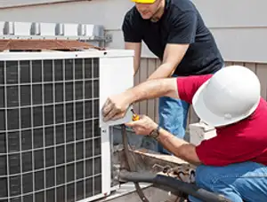 HVAC technicians repairing an outdoor AC unit on a rooftop in Bloomington, IN