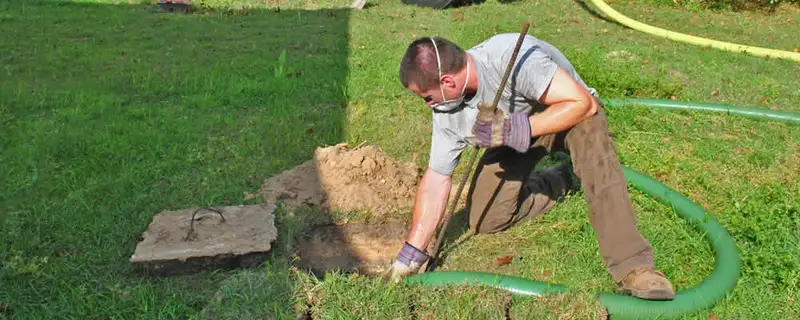 Septic pumping technician servicing a residential septic tank in Bloomington, IN