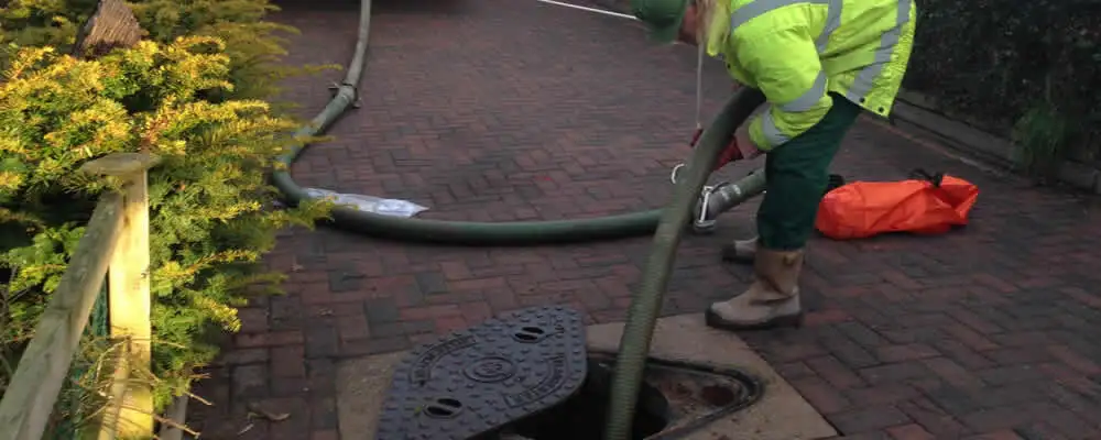 Septic tank cleaning technician servicing a septic tank with a vacuum hose in Bloomington, IN