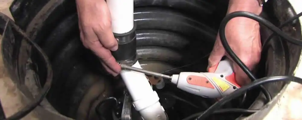 Sump pump installation technician connecting PVC discharge piping in Bloomington, IN