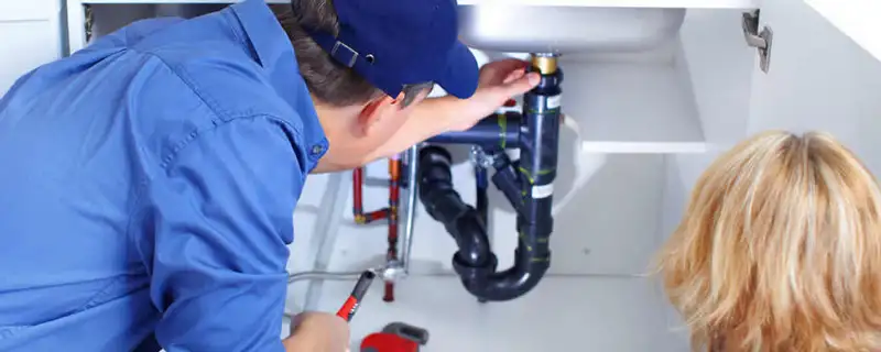Plumber repairing under-sink drain pipes and fittings in Bloomington, IN